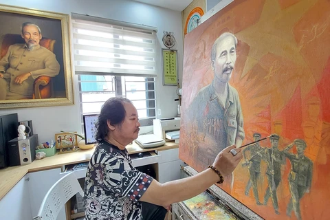 Họa sỹ Trần Xuân Phúc bên tác phẩm khắc họa Chủ tịch Hồ Chí Minh với lực lượng vũ trang. (Ảnh: Minh Thu/Vietnam+)