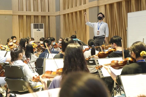 Nhạc trưởng Phan Đỗ Phúc tập luyện cùng dàn nhạc trẻ đa quốc tịch đầu tiên tại Việt Nam. (Ảnh: PV/Vietnam+)