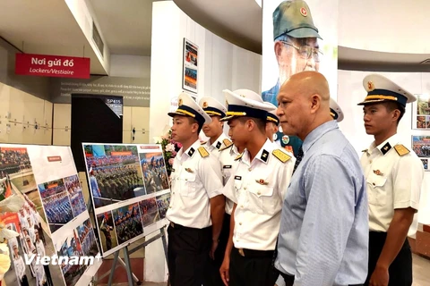 Nhiếp ảnh gia Nguyễn Á cùng các chiến sỹ hải quân tham quan triển lãm. (Ảnh: Minh Thu/Vietnam+)