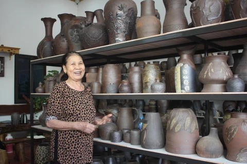 Bà Giang Thị Nhạn bên những tác phẩm gốm của xưởng nhà. (Ảnh: Minh Anh/Vietnam+)