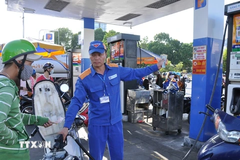 Nhân viên Petrolimex đang bán xăng cho khách hàng (Ảnh: TTXVN)