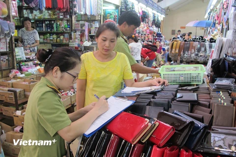Lực lượng quản lý thị trường Hà Nội đang ký cam kết với các tiểu thương chợ Đồng Xuân về chống buôn lậu (Ảnh: Đức Duy/Vietnam+)