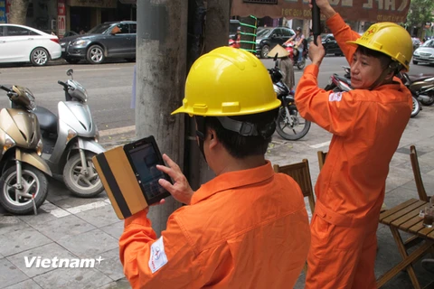 Nhân viên Tổng Công ty Điện lực Hà Nội đang ghi chỉ số công tơ của khách hàng (Ảnh: Đức Duy/Vietnam+)
