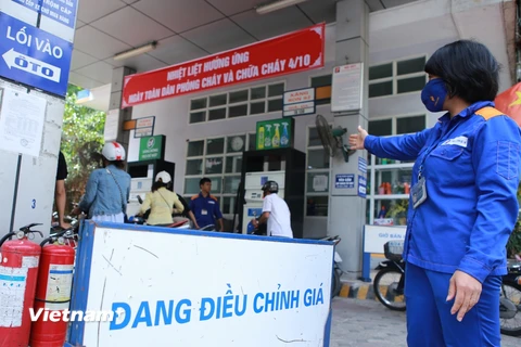 Nhân viên Petrolimex hướng dẫn khách hàng mua xăng trước khi điều chỉnh giá (Ảnh: Đức Duy/Vietnam+)