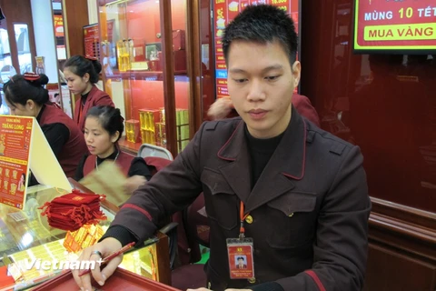 Nhân viên Bảo Tín Minh Châu kiểm tra vàng miếng trước khi giao dịch với khách hàng. (Ảnh: Đức Duy/Vietnam+)