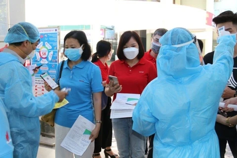 Kiểm tra khai báo y tế, thân nhiệt cho người lao động Dầu khí trước khi bước vào khu vực tiêm chủng. (Ảnh: PV/Vietnam+)