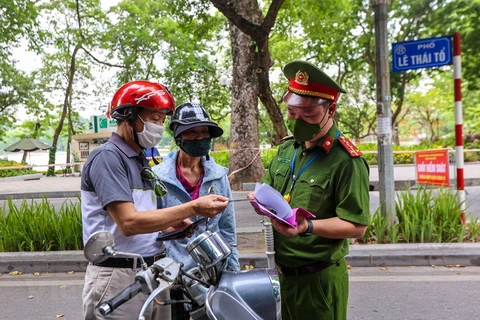 Lực lượng chức năng nhắc nhở người dân thực hiện nghiêm công tác phòng, chống dịch. (Ảnh: Minh Sơn/Vietnam+)