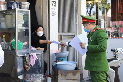 Trong ảnh: Công an phường Nguyễn Du nhắc nhở các hộ kinh doanh thực nghiêm chỉ đạo của UBND quận Hai Bà Trưng. (Ảnh: TTXVN)