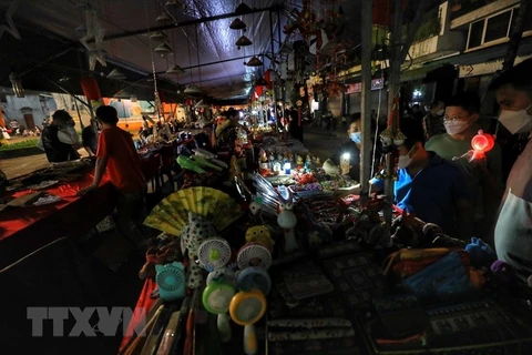 Chợ đêm trên phố Hàng Dầu tắt điện và sử dụng ánh sáng của điện thoại. (Ảnh: Tuấn Đức/TTXVN)