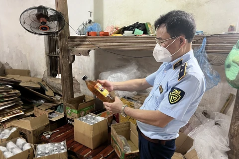 Cán bộ Đội Quản lý thị trường số 24 đang kiểm tra số mật ong vừa tạm giữ tại một cơ sở trên địa bàn huyện Hoài Đức, Hà Nội. (Ảnh: PV/Vietnam+)