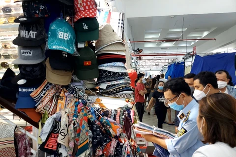 Lực lượng Quản lý thị trường kiểm tra hàng hóa tại một kiốt của Trung tâm mua sắm Sài Gòn Square. (Ảnh: PV/Vietnam+)