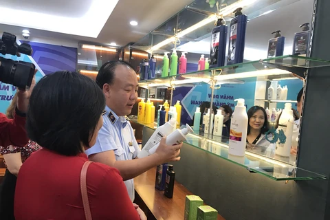 Ông Trần Hữu Linh, Tổng cục trưởng Tổng cục Quản lý thị trường hướng dẫn phân biệt hóa mỹ phẩm giả. (Ảnh: Xuân Quảng/Vietnam+)