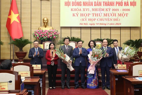 Bí thư Thành ủy Hà Nội Đinh Tiến Dũng tặng hoa chúc mừng bà Vũ Thu Hà (áo dài xanh) được bầu làm Phó Chủ tịch Ủy ban Nhân dân thành phố Hà Nội. (Ảnh: PV/Vietnam+)