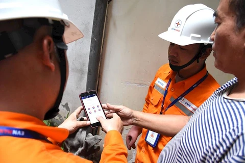 Nhân viên EVNHANOI hướng dẫn khách hàng kiểm tra hóa đơn điện ngay trên App EVNHANOI. (Ảnh: evnhanoi)