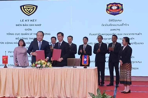 Tổng Cục trưởng Tổng cục Quản lý Thị trường Trần Hữu Linh và Vụ trưởng Vụ Cạnh tranh kinh doanh và Kiểm tra Thương mại Lào triển khai ký cam kết trong lĩnh vực quản lý thị trường. (Ảnh: PV/Vietnam+)