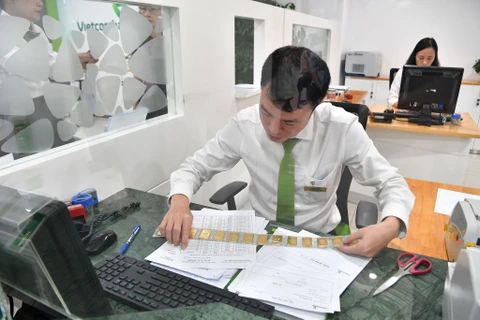 Nhân viên ngân hàng Vietcombank chuẩn bị bán vàng cho khách hàng. (Ảnh: PV/Vietnam+)