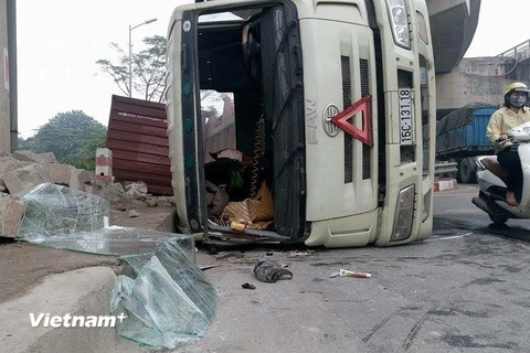 Chiếc xe container bị đổ nghiêng tại gầm đường trên cao rạng sáng ngày 1/12. (Ảnh: Minh Sơn/Vietnam+)