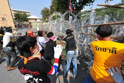 Những người biểu tình chống chính phủ phá hàng rào bên ngoài tòa nhà chính phủ ở thủ đô Bangkok ngày 12/12. (Nguồn: THX/TTXVN)