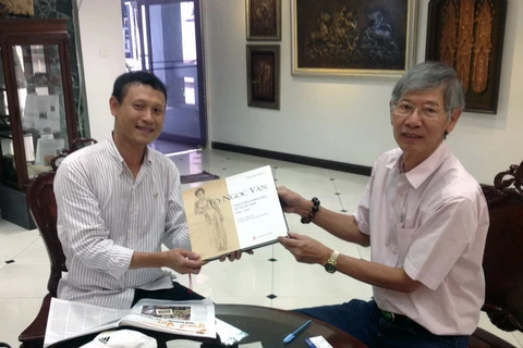Phóng viên Vietnam+ được ông Tira tặng cuốn sách Tô Ngọc Vân - tấm gương phản chiếu xã hội Việt Nam 1906-1954. (Ảnh: Hà Linh/Vietnam+)