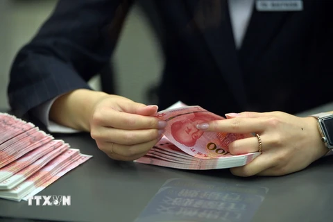 Nhân viên ngân hàng kiểm tiền 100 nhân dân tệ mới tại một ngân hàng ở Bắc Kinh. (Nguồn: THX/TTXVN)