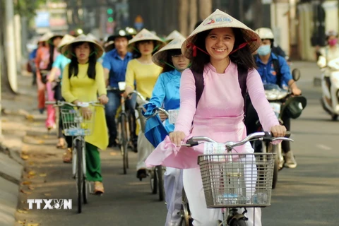 Các tình nguyện viên tham gia đạp xe với trang phục áo dài truyền thống qua các tuyến đường trung tâm Thành phố. (Ảnh: An Hiếu/TTXVN)