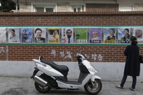 Một người phụ nữ nhìn ápphích tranh cử của ứng cử viên cuộc bầu cử quốc hội tại Seoul, Hàn Quốc. (Nguồn: AP)