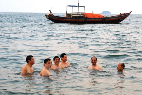 Giám đốc Sở Tài nguyên và Môi trường Hà Tĩnh cùng các du khách tắm biển tại bãi tắm Thiên Cầm, chiều 30/4. (Ảnh: Phan Quân/TTXVN)