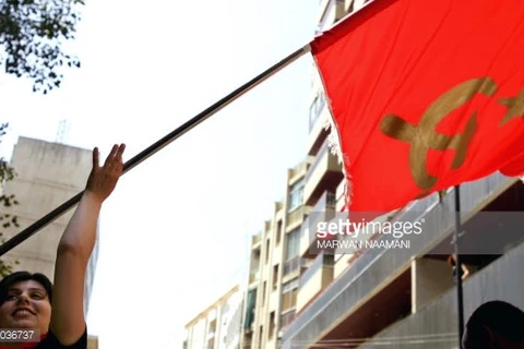Một người phụ nữ trẻ cầm cờ của Đảng cộng sản Liban. (Nguồn: Getty Images)