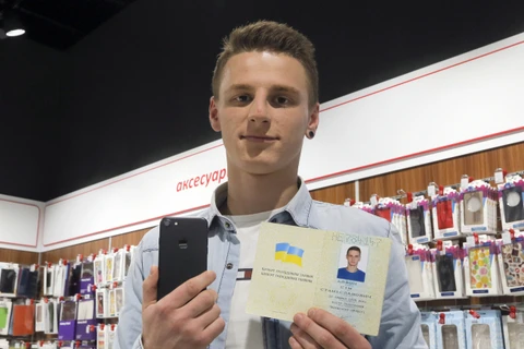 "iPhone 7" bên chiếc iPhone 7 của mình và cuốn hộ chiếu đã đổi tên tại một cửa hàng điện tử ở Kiev, Ukraine. (Nguồn: AP)