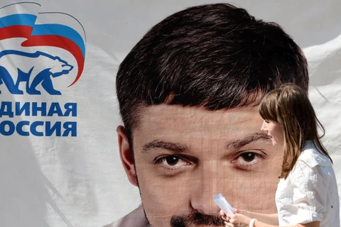 Một người phụ nữ đi qua một tấm poster có hình ông Andrei Kozenko, 1 trong 6 nghị sỹ Nga bị đưa vào danh sách đen của Mỹ. (Nguồn: AFP)