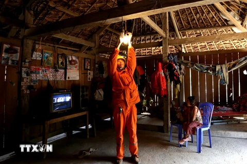 Công nhân Công ty Điện lực Thái Nguyên lắp đèn tiết kiệm điện và hướng dẫn người dân sử dụng điện an toàn. (Ảnh: Ngọc Hà/TTXVN)