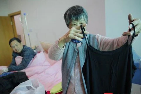 Ông Tân Nguyệt và người vợ trong phòng bệnh. Bà từng mua cho ông nhiều quần áo nữ. (Nguồn: southcn.com)