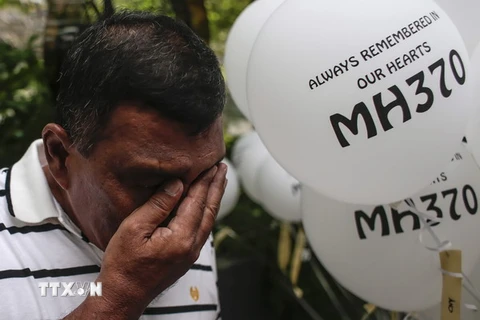 Người phụ nữ xem lại bức ảnh gia đình người em gái, họ vẫn chưa trở về cùng máy bay MH370. (Nguồn: QQ)