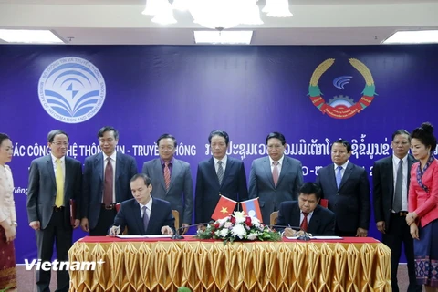 Đại diện Học viện công nghệ bưu chính viễn thông Việt Nam và Học viện Công nghệ thông tin và truyền thông Lào đang ký Biên bản thỏa thuận hợp tác. (Ảnh: Phạm Kiên/Vietnam+)