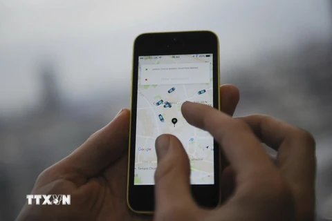 Một khách hàng sử dụng điện thoại di động để gọi dịch vụ xe của Uber. (Nguồn: AFP/TTXVN)
