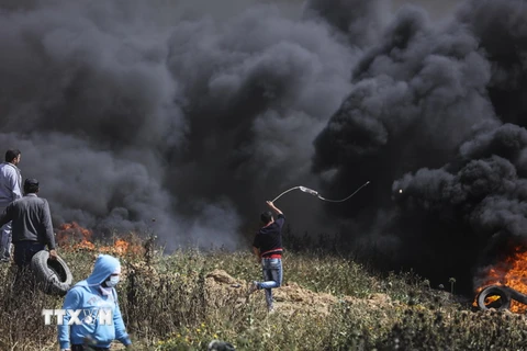 Người biểu tình Palestine đốt lốp xe và ném đá vào binh sỹ Israel trong cuộc biểu tình dọc biên giới giữa khu vực phía Đông Dải Gaza và Israel. (Nguồn: THX/TTXVN) 