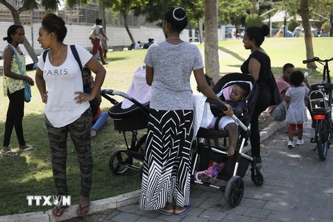 Các gia đình người tị nạn châu Phi nghỉ ngơi gần một công viên ở Tel Aviv. (Nguồn: AFP/TTXVN)