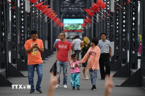 Du khách tham quan cây cầu Hữu Nghị nối giữa thành phố Dandong và thị trấn Sinuiju của Triều Tiên. (Nguồn: AFP/TTXVN)