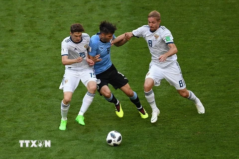 Pha tranh bóng giữa cầu thủ Rodrigo Bentancur (giữa) đội Uruguay và các cầu thủ Yuri Gazinskiy (phải) và Aleksey Miranchuk (trái) đội Nga . (Nguồn: AFP/TTXVN)