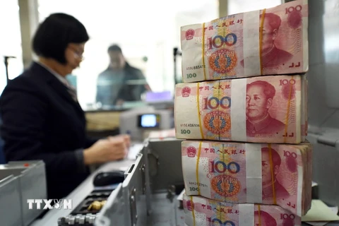 Kiểm tiền 100 tệ tại ngân hàng ở Liên Vận Cảng, tỉnh Giang Tô, Trung Quốc. (Nguồn: AFP/TTXVN)