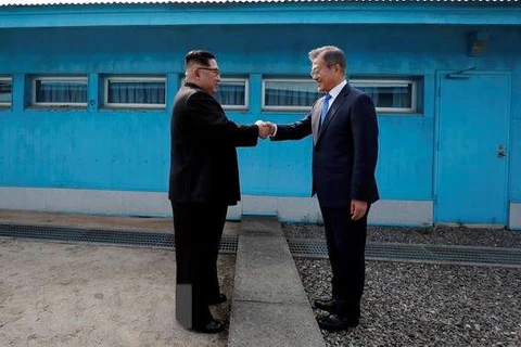 Tổng thống Hàn Quốc Moon Jae-in (phải) đón Nhà lãnh đạo Triều Tiên Kim Jong-un ở đường phân định ranh giới giữa hai miền tại làng đình chiến Panmunjom. (Nguồn: TTXVN)