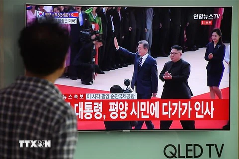 Người dân Hàn Quốc tại thủ đô Seoul theo dõi hình ảnh truyền hình trực tiếp Nhà lãnh đạo Triều Tiên Kim Jong-un (giữa, phía xa) đón Tổng thống Hàn Quốc Moon Jae-in (trái, phía xa) tại sân bay quốc tế Bình Nhưỡng ngày 18/9/2018. (Nguồn: AFP/TTXVN)