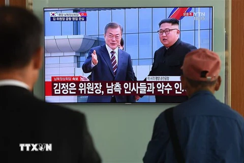 Người dân Hàn Quốc tại thủ đô Seoul theo dõi hình ảnh truyền hình trực tiếp Nhà lãnh đạo Triều Tiên Kim Jong-un (phải, phía xa) đón Tổng thống Hàn Quốc Moon Jae-in (trái, phía xa) tại sân bay quốc tế Bình Nhưỡng ngày 18/9/2018. (Nguồn: AFP/TTXVN)