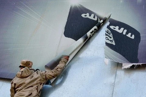 Một binh sỹ Iraq xé cờ của tổ chức IS. (Nguồn: AFP)