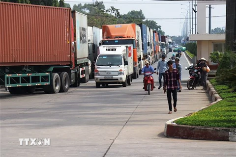 Các phương tiện vận tải chờ đóng phí hạ tầng để xuất cảnh qua cửa khẩu quốc tế Mộc Bài. (Ảnh: Lê Đức Hoảnh/TTXVN) 