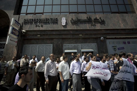 Viên chức Palestine xếp hàng yêu cầu được nhận lương bên ngoài Ngân hàng Palestine ở thành phố Gaza. (Nguồn: AFP/TTXVN) 