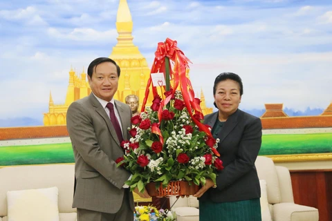 Đại sứ Việt Nam tại Lào Nguyễn Bá Hùng (trái) trao hoa chúc mừng cho Trưởng Ban Đối ngoại Trung ương Đảng nhân dân cách mạng Lào Sounthon Xayachak. (Ảnh: Xuân Tú/TTXVN)