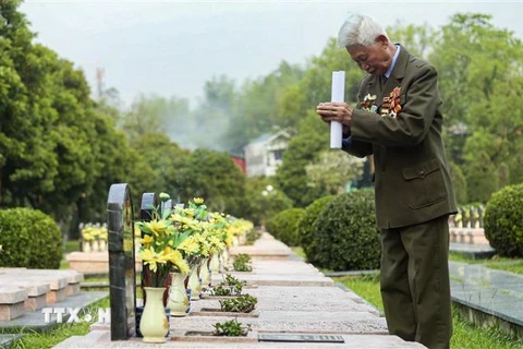 Một cựu chiến binh thắp hương cho đồng đội tại Nghĩa trang Liệt sỹ A1. (Ảnh: Xuân Tư/TTXVN) 