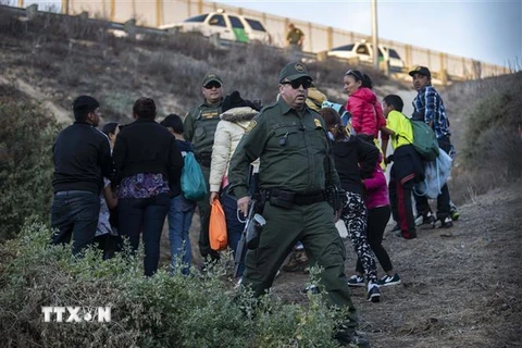 Người di cư Trung Mỹ bị cảnh sát Mỹ bắt giữ sau khi cố vượt qua hàng rào vào Mỹ. (Nguồn: AFP/TTXVN) 