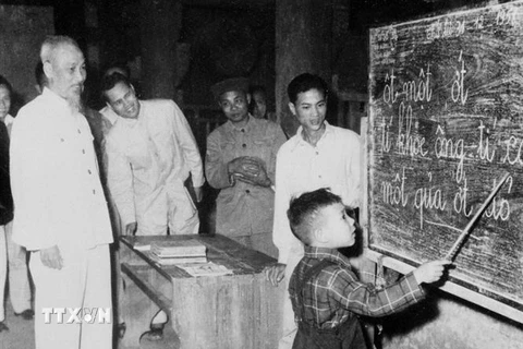 Chủ tịch Hồ Chí Minh quan sát một cháu thiếu nhi tập đánh vần khi đến thăm lớp vỡ lòng Đình Thạch Khối ở phố Hàng Than, Hà Nội (31/12/1959). (Nguồn: TTXVN) 